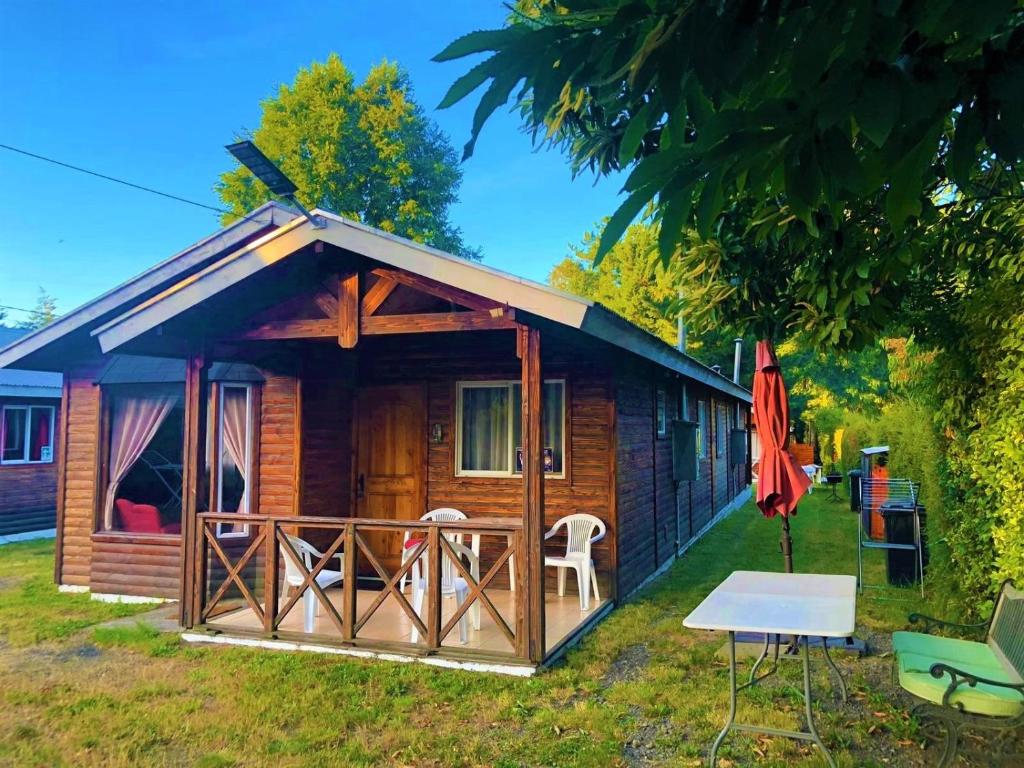 een blokhut met een tafel en een paraplu bij CABAÑAS MILKAHUE PUCON in Pucón