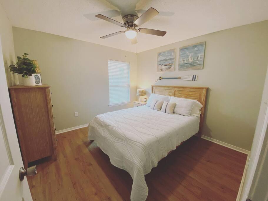a bedroom with a bed and a ceiling fan at White Sand Getaway steps from Beach in Gulfport