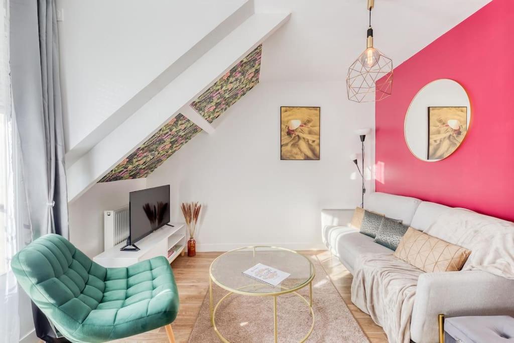 ein Wohnzimmer mit einem weißen Sofa und einer rosa Wand in der Unterkunft Duplex les Oiseaux du Verger, au coeur de la ville in Verneuil-sur-Seine