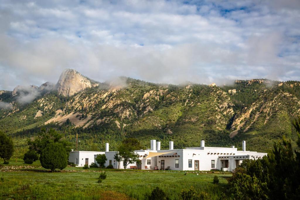 um grande edifício branco em frente a uma montanha em Casa del Gavilan Historic Inn em Cimarron