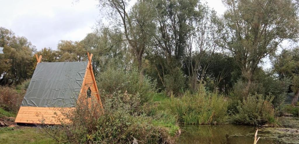 een huis met een groen dak naast een rivier bij Rum Bridge "Owl Watch" wooden tipi in Sudbury