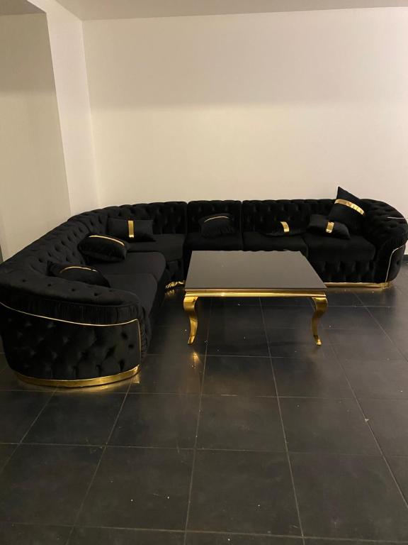 ein Wohnzimmer mit einem schwarzen Sofa und einem Tisch in der Unterkunft Appartement 2 chambre luxueuse à jette in Brüssel