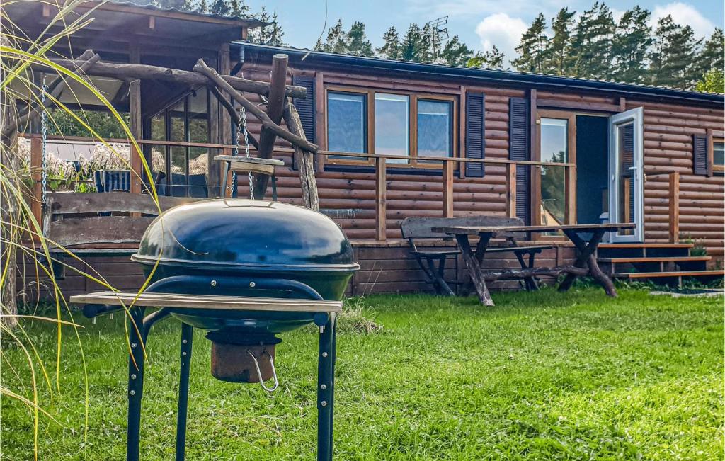 a grill in front of a log cabin at Pet Friendly Home In Biskupiec With Lake View in Biskupiec