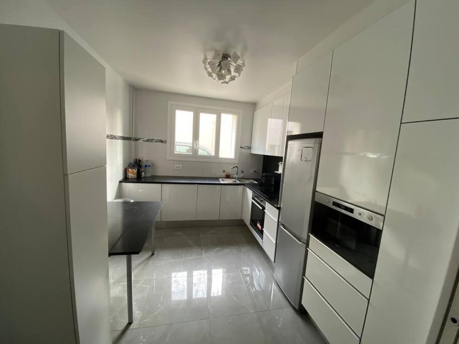 cocina blanca con fregadero y nevera en Superbe appartement Vanves T3 avec parking en Vanves
