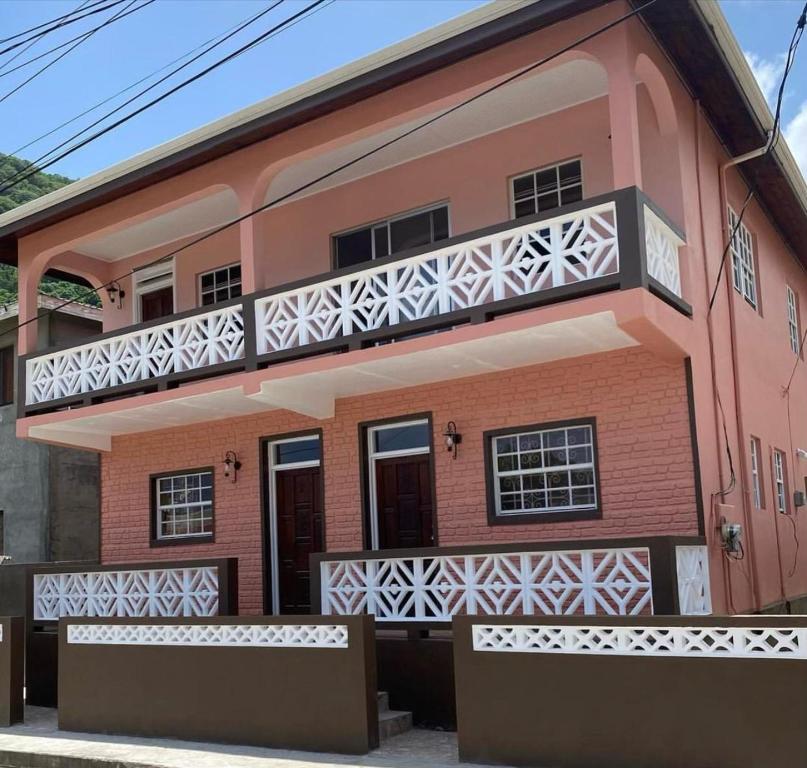 una casa rosa con balcón en Coco Rose Apartments en Soufrière