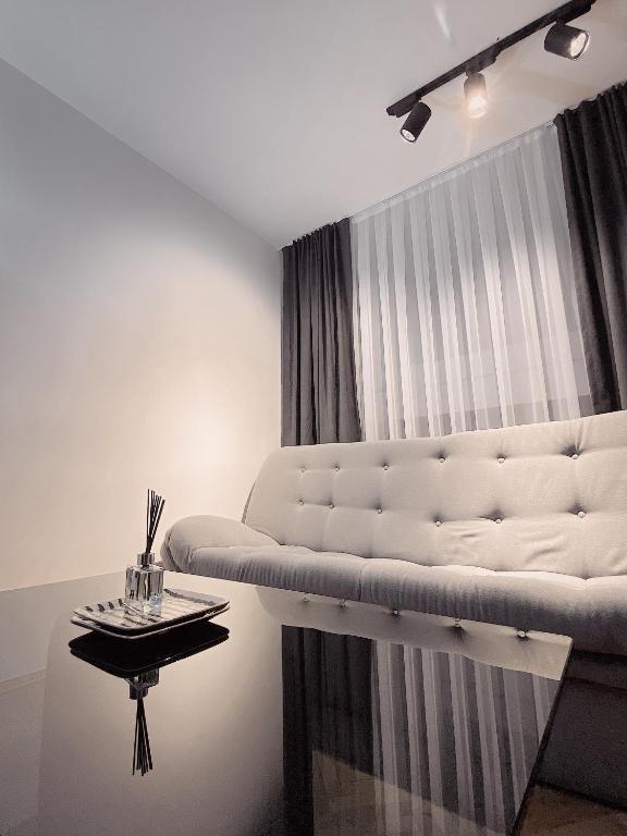 ein Wohnzimmer mit einer weißen Couch und einem Tisch in der Unterkunft Diamond Apartment Prishtina 2 in Pristina