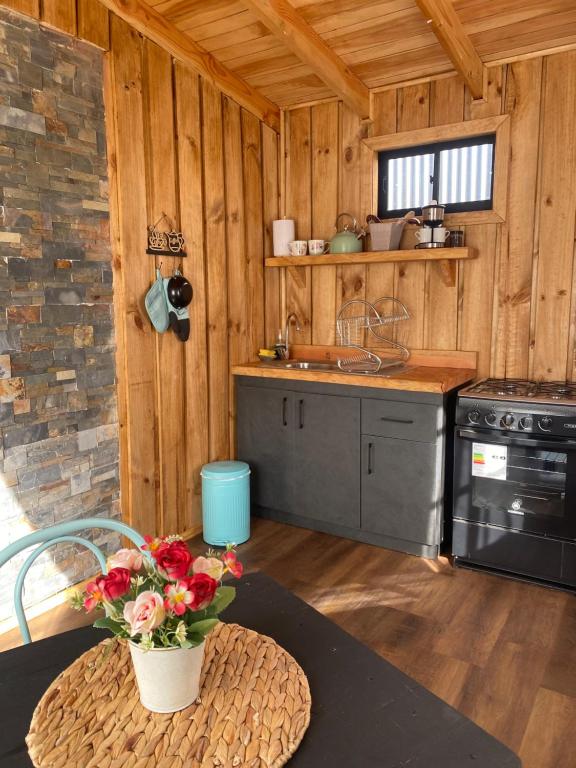 a kitchen with a stove and a table with a vase of flowers at El Encanto de Antilhue in Valdivia