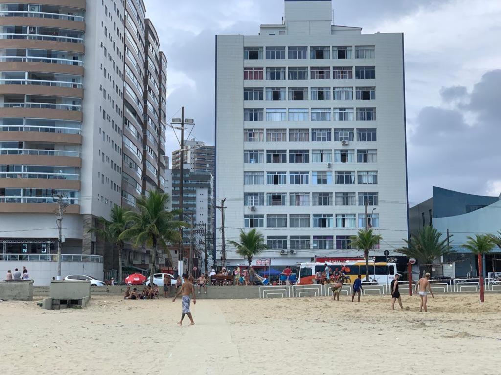 Un grupo de personas en una playa con edificios. en Apartamento no Boqueirão com vista para o mar e pé na areia, en Praia Grande