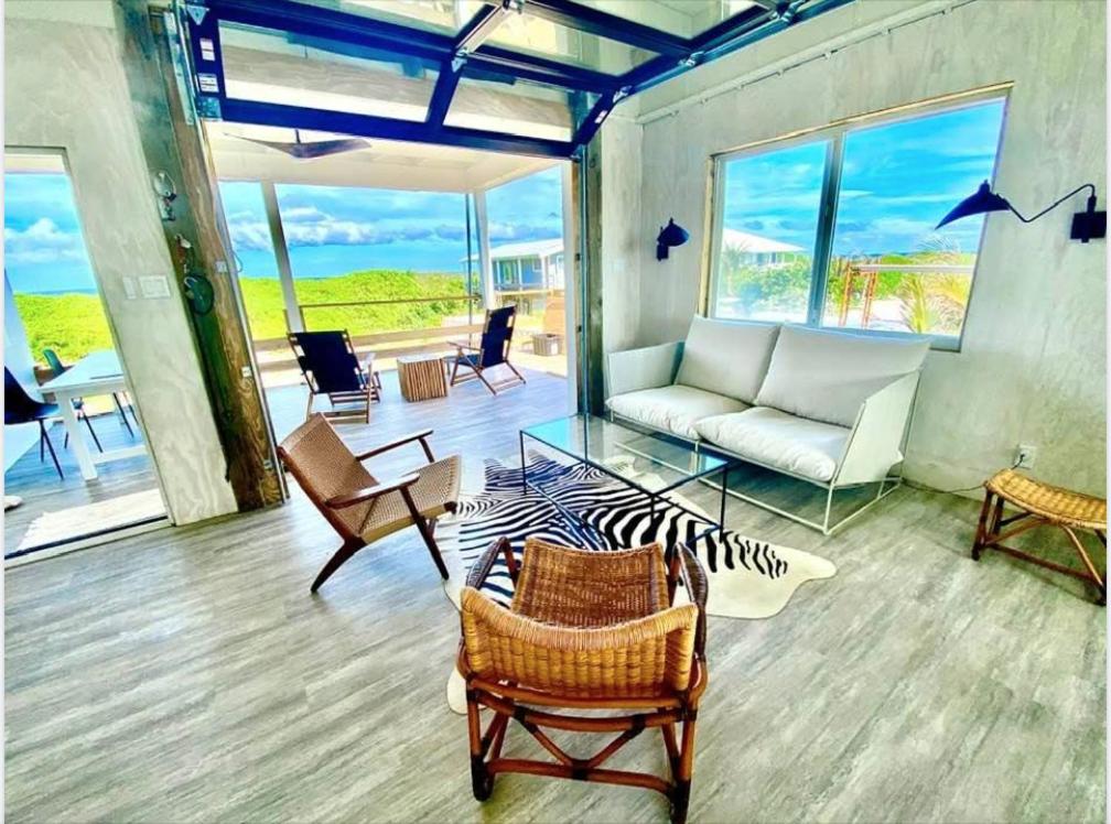 uma sala de estar com um sofá, uma mesa e cadeiras em Rooster Beach - Hope Town, Elbow Cay em Lubbers Quarters Cay