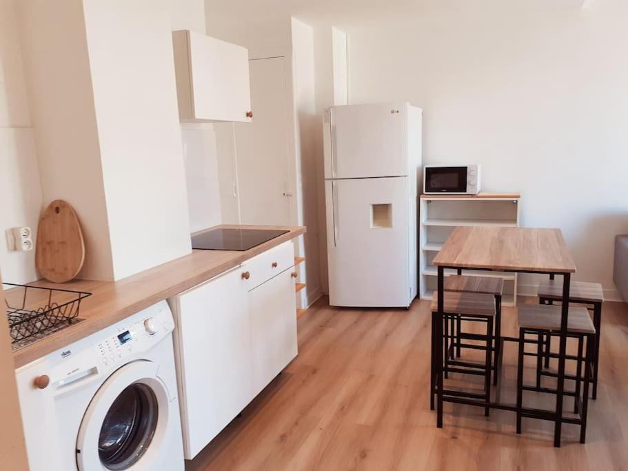 eine Küche mit einer Waschmaschine, einem Tisch und einem Kühlschrank in der Unterkunft Grenoble appartement pour 4 proche du centre ville in Grenoble