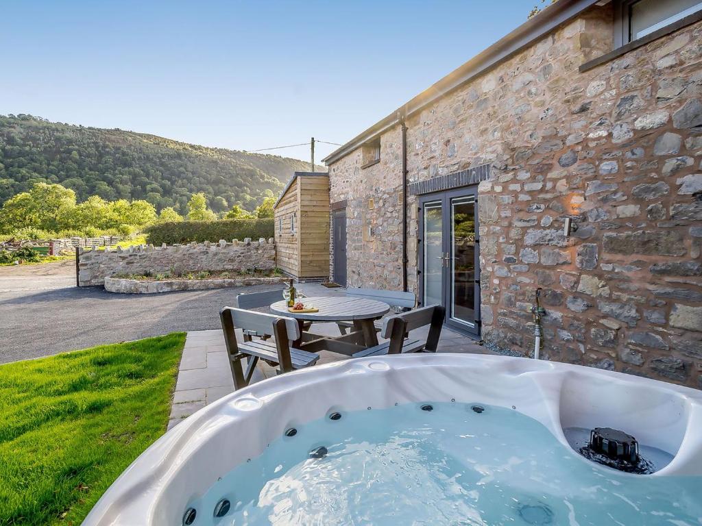 a bath tub in the yard of a stone house at Ty Godro - Uk12745 in Acrefair