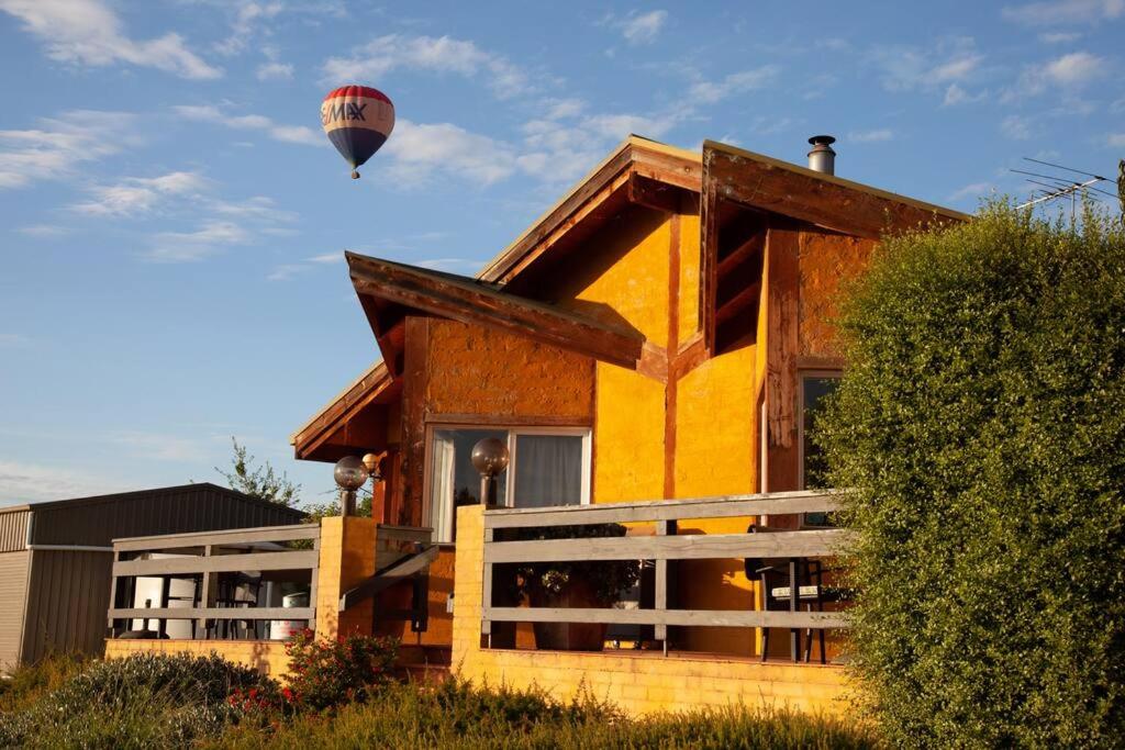 a hot air balloon flying over a house at Rose Cottage. Cosy, eco-friendly cottage in Yarra Glen. in Yarra Glen