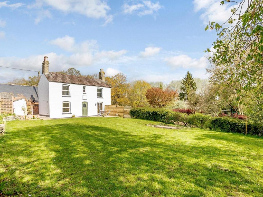 a white house with a large grass yard at Spinney Cottage in Woodford