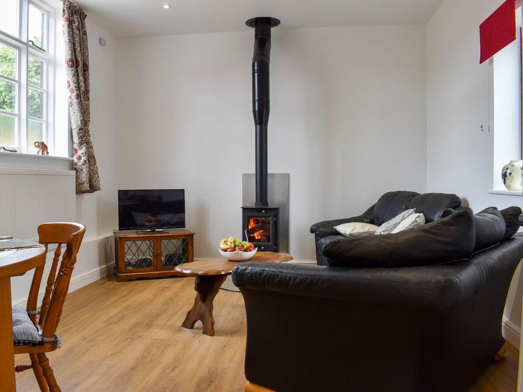 a living room with a black leather couch and a fireplace at Fallow Cottage - Uk33488 in Hadleigh