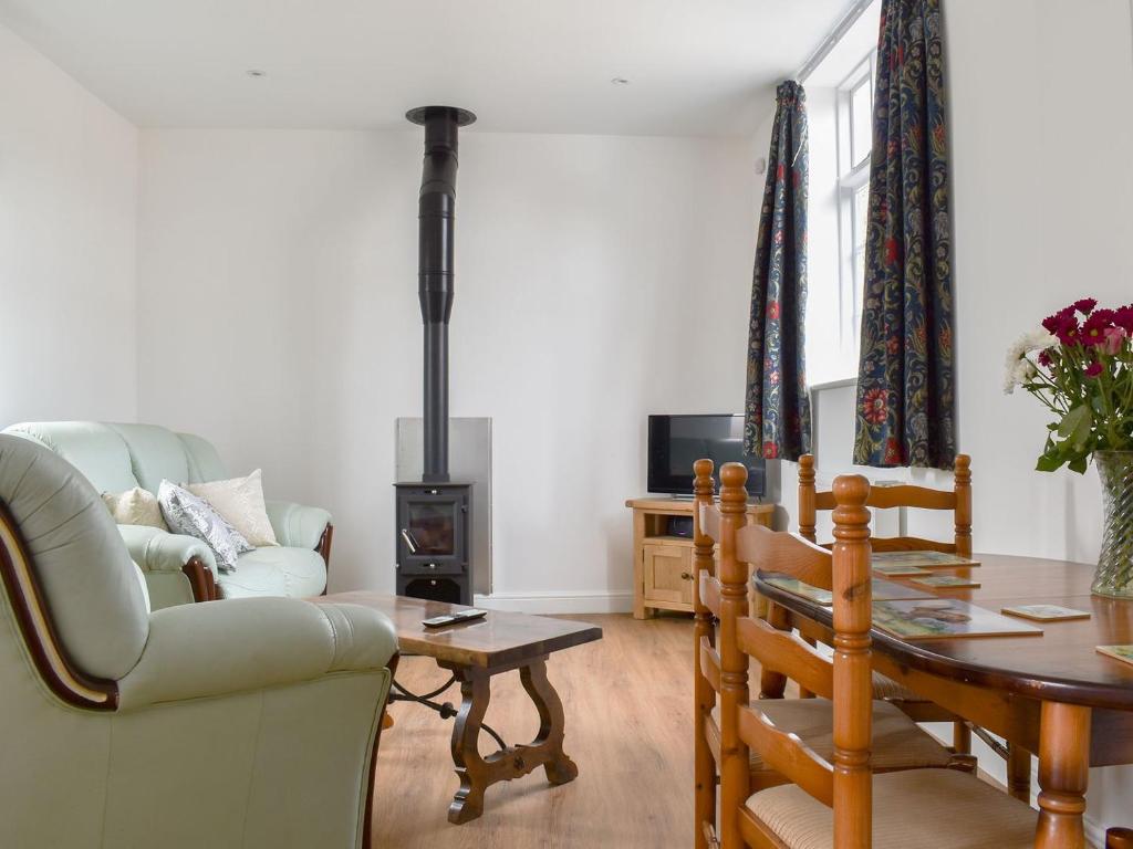 a living room with a table and a wood stove at Roe Cottage - Uk33490 in Hadleigh