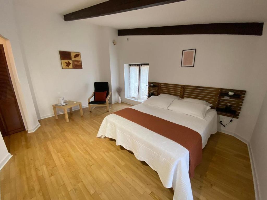 sypialnia z dużym łóżkiem i krzesłem w obiekcie Lou Cantou w mieście Nègrepelisse