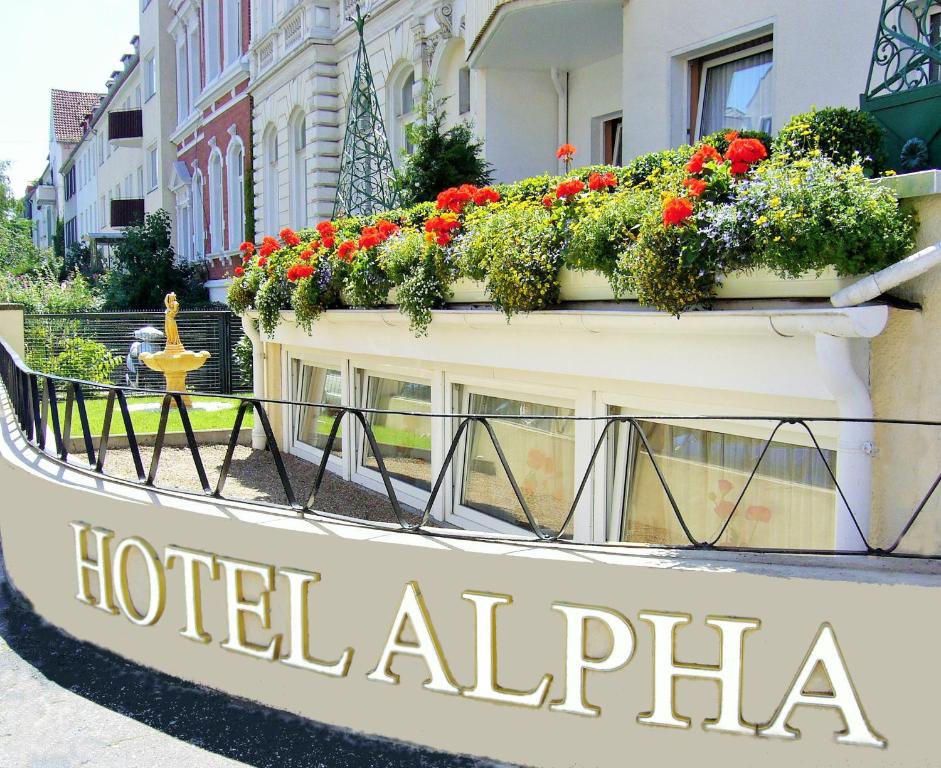 een bord voor een hotel alfa met bloemen op een gebouw bij Hotel Alpha in Hannover