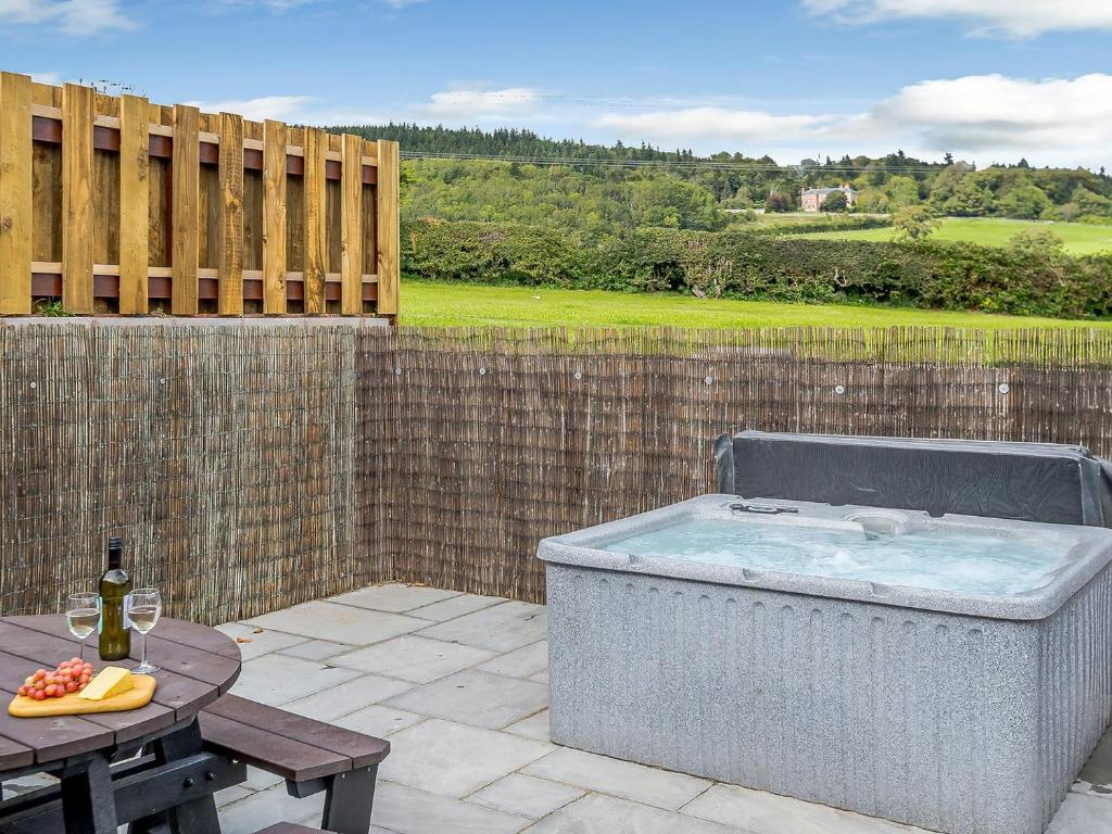 a hot tub on a patio with a table at Y Stabl - Uk12742 in Acrefair