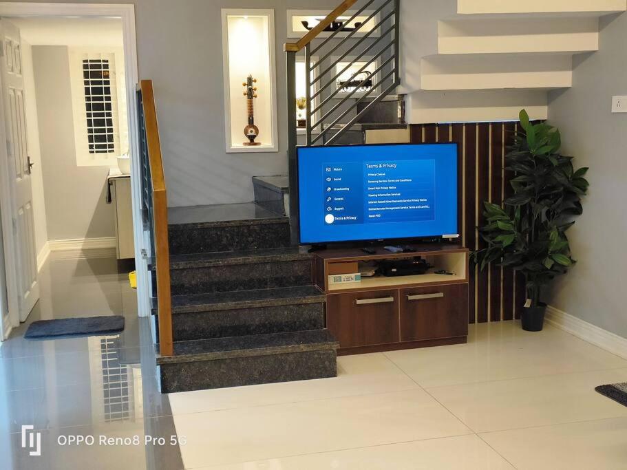 a television in a living room with a staircase at Peppercorn Cottage, Vythiri. in Vythiri