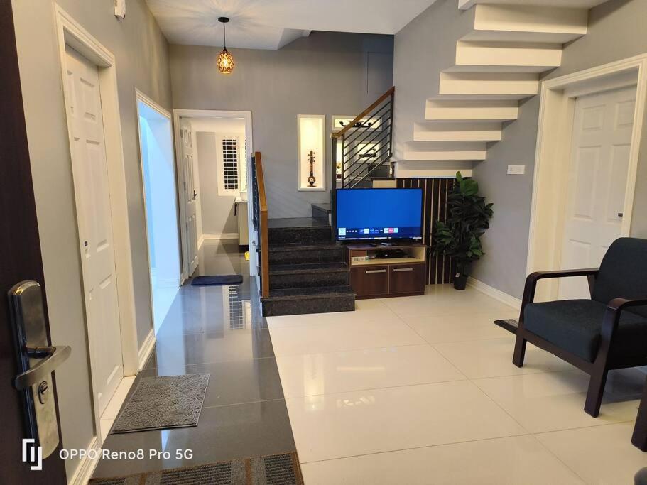 a living room with a television and a staircase at Peppercorn Cottage, Vythiri. in Vythiri