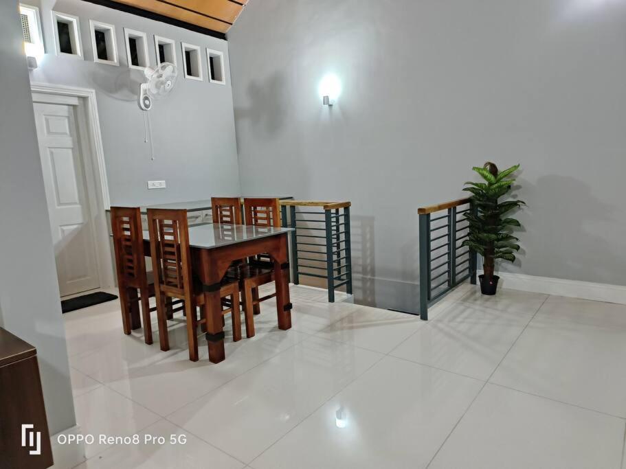 a dining room with a table and chairs and a plant at Peppercorn Cottage, Vythiri. in Vythiri