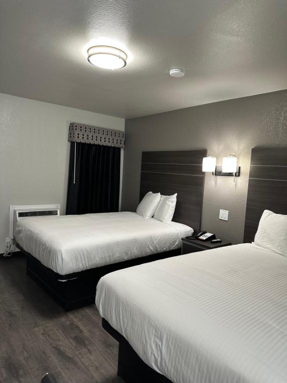 una camera d'albergo con due letti con lenzuola bianche di Sleepy Traveler Motel a Wagoner