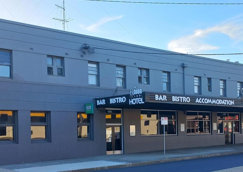 a gray building with a bar studiokluthuation signs on it at Union Club Hotel in Colac