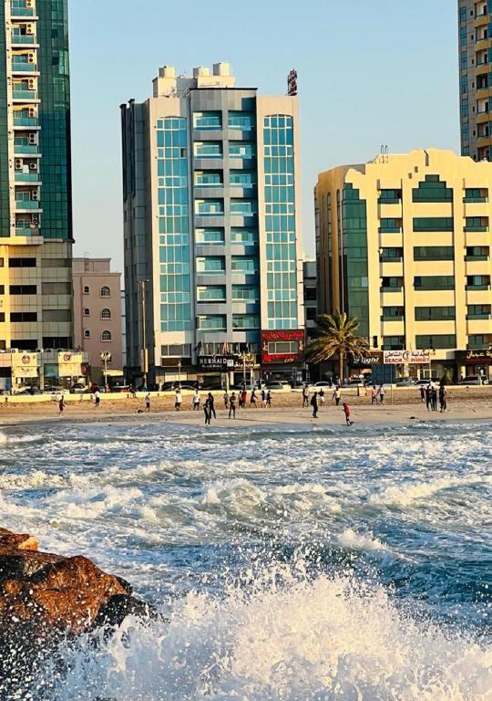 een strand met hoge gebouwen en mensen in het water bij Mermaid Beach Hotel LLC in Ajman 