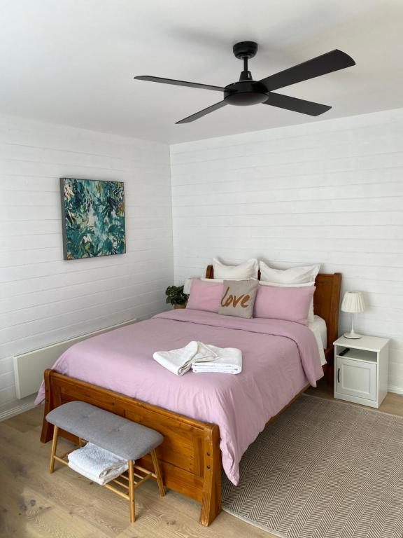 Cette chambre comprend un lit avec des draps roses et un ventilateur de plafond. dans l'établissement Beautiful Guesthouse in Monbulk, à Monbulk