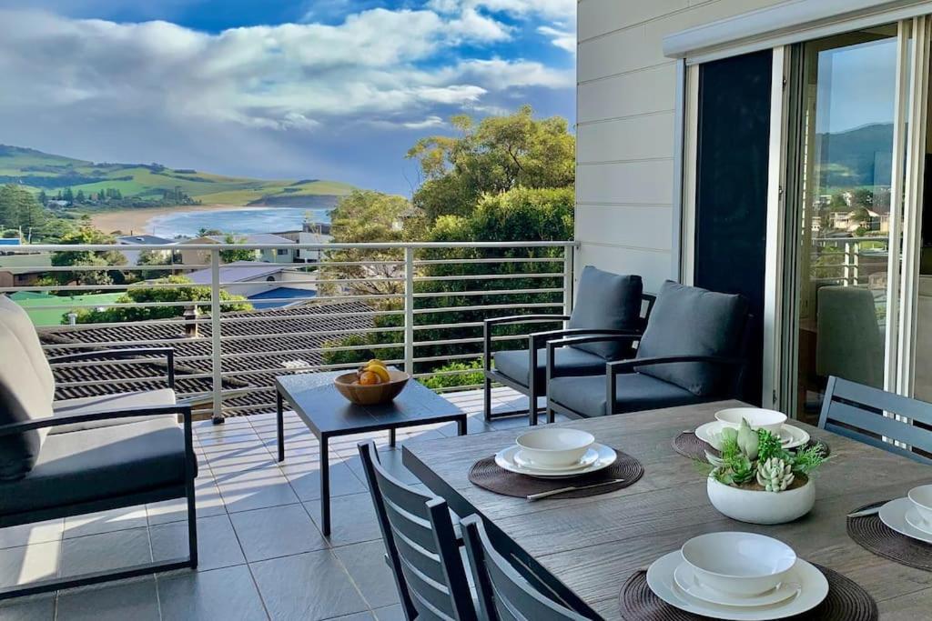 a patio with a table and chairs on a balcony at Seaview at Gerringong - 4pm check out if available in Gerringong