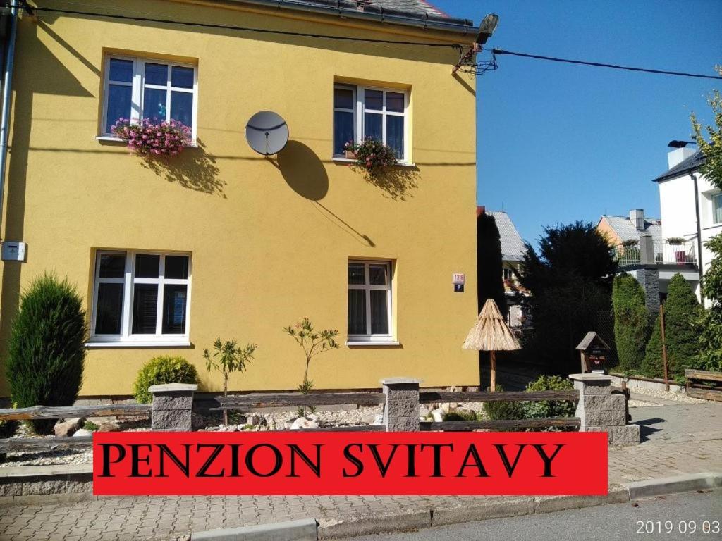 une maison jaune avec un panneau devant elle dans l'établissement Penzion Svitavy, à Svitavy