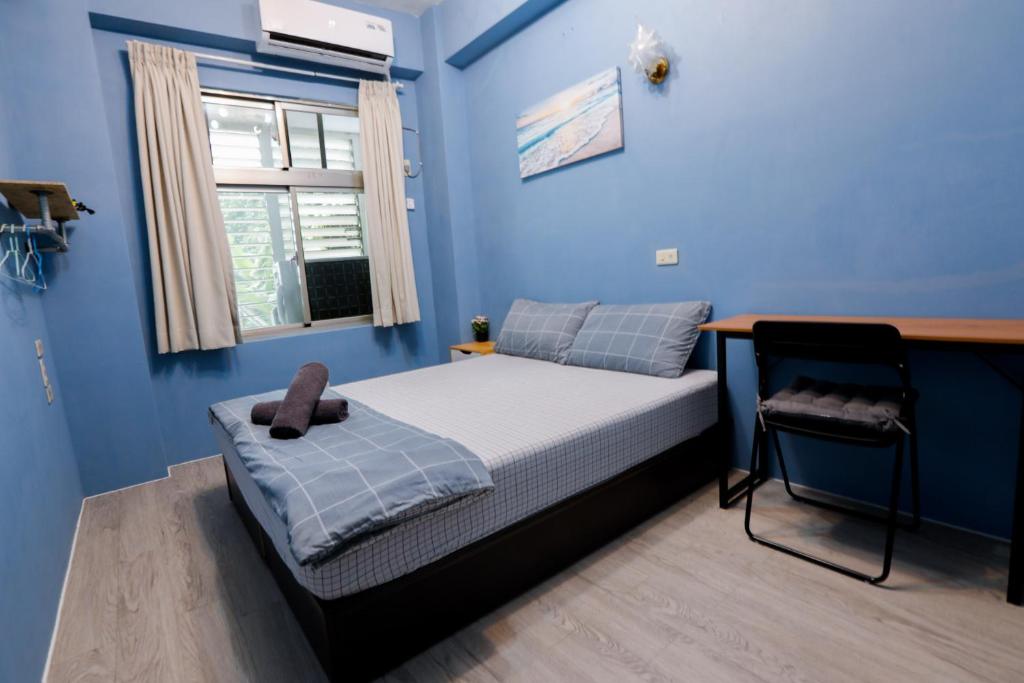 a bedroom with blue walls and a bed with a desk at Green Island Ocean Rhythem dive B&B 綠島海韻民宿 in Green Island