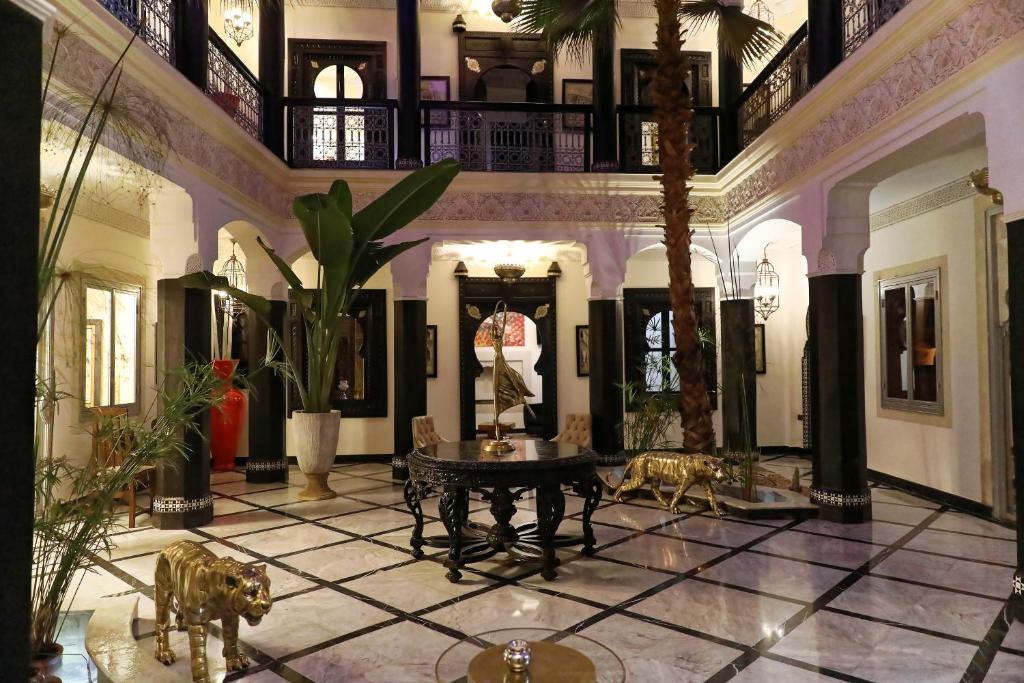 um grande átrio com uma mesa e palmeiras em Palais-Riad Razala & Spa em Marrakech