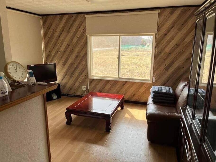 a living room with a couch and a coffee table at 暮らすように過ごす温泉宿　白老大使館 in Shiraoi