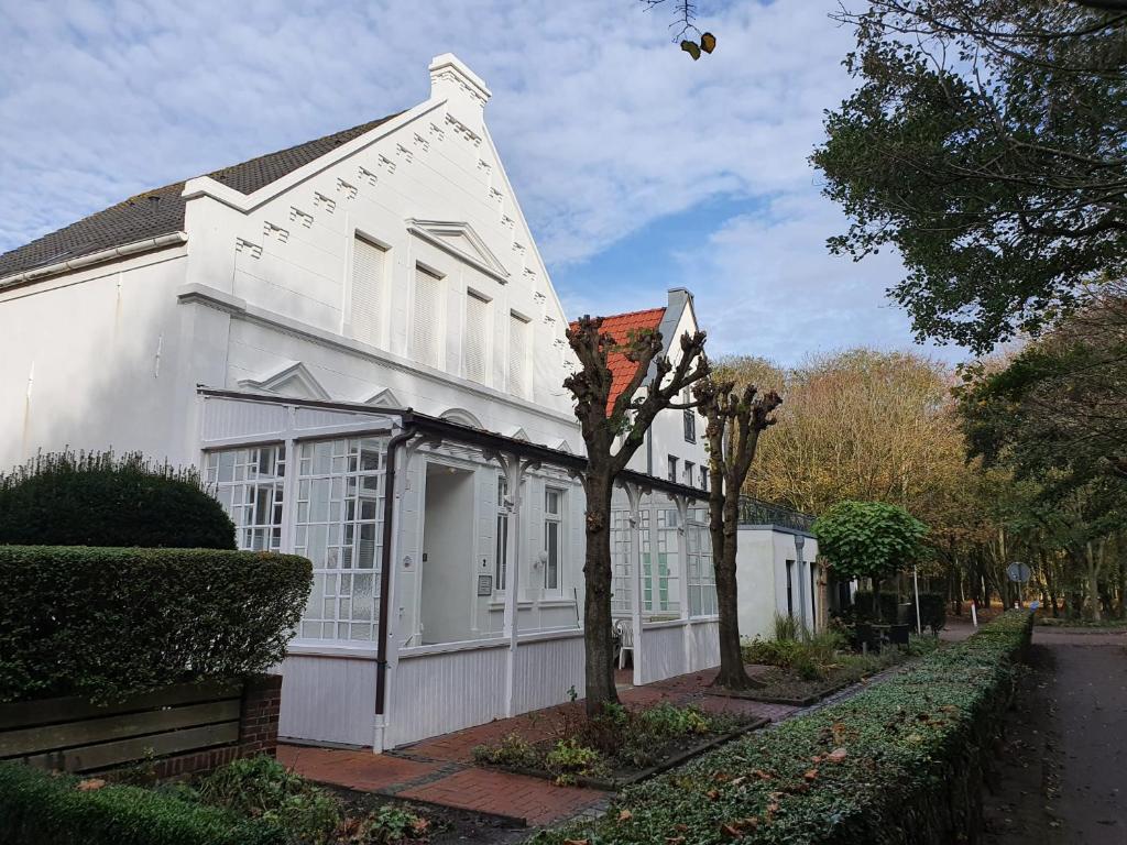 een wit gebouw met een boom ervoor bij Haus Fischer in Norderney