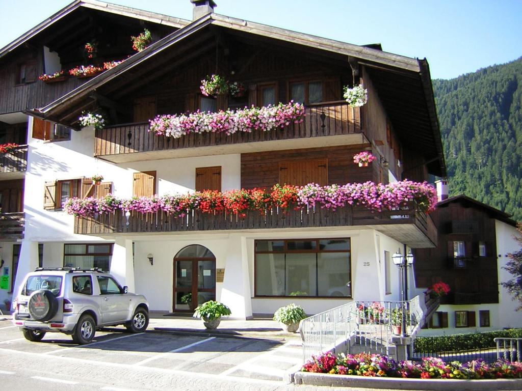 une petite voiture garée devant un immeuble fleuri dans l'établissement Auronzo Vacanze di Marina e Valter - Corte 25, à Auronzo di Cadore