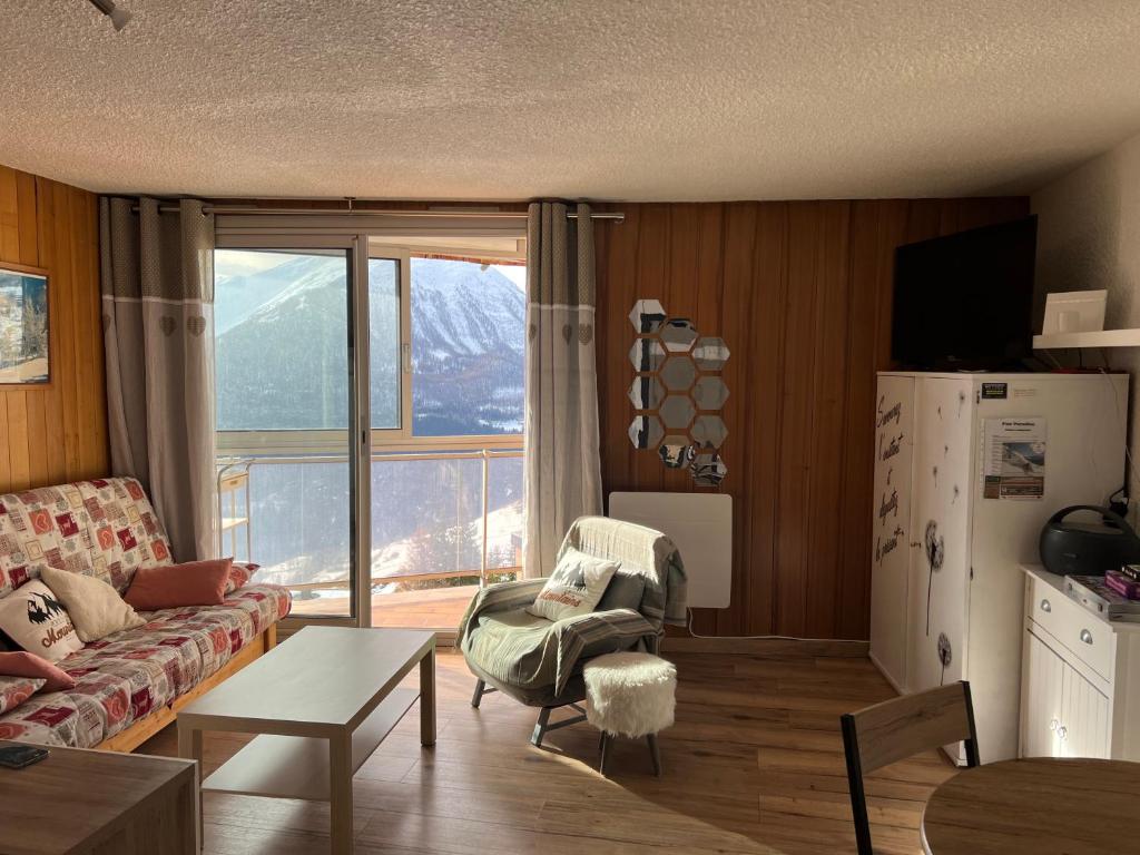 uma sala de estar com um sofá e uma grande janela em Appartement station Orcieres merlette em Orcières
