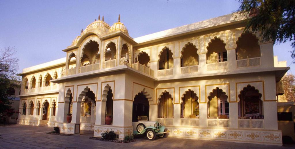 een oude auto geparkeerd voor een gebouw bij Hotel Bissau Palace in Jaipur