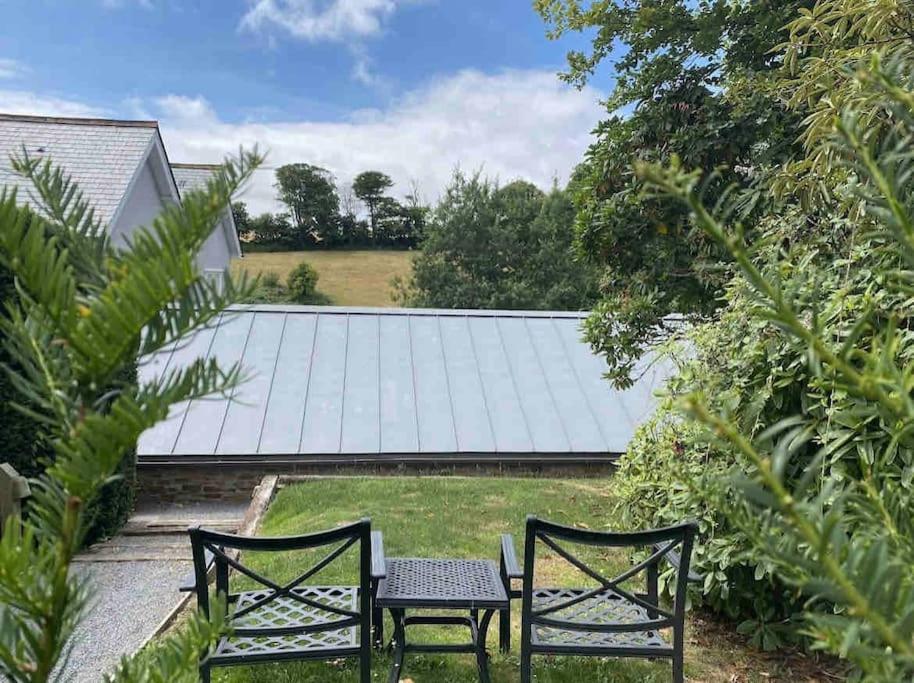 2 sillas y una mesa frente a un techo solar en The Loft Apartment @ Lower Coombe Royal, en Kingsbridge