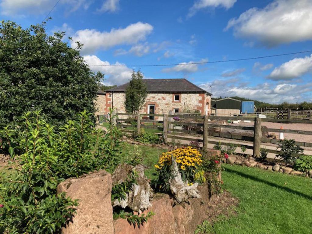 un jardín con flores frente a un edificio en Cosy 2-Bed Cottage with Garden near Carlisle, en Longtown