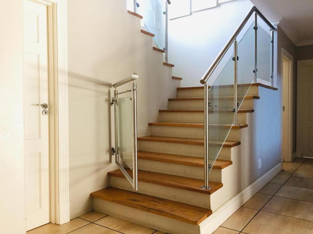 una escalera con barandillas de cristal en una casa en Harbour Close Boutique Villa en Ciudad del Cabo