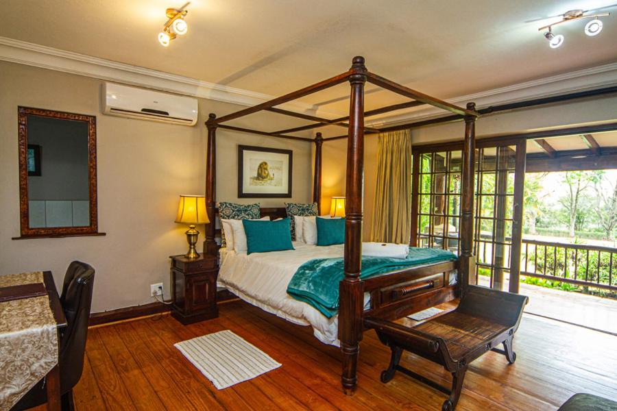 1 dormitorio con cama con dosel y balcón en Kangelani Lodge, en Hillcrest