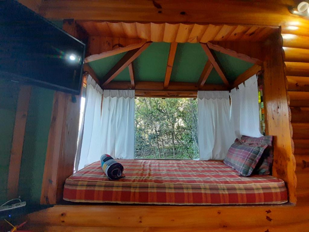 a bed in a log cabin with a window at Cabañas con costa al lago, Kalfulafquen in Villa La Angostura