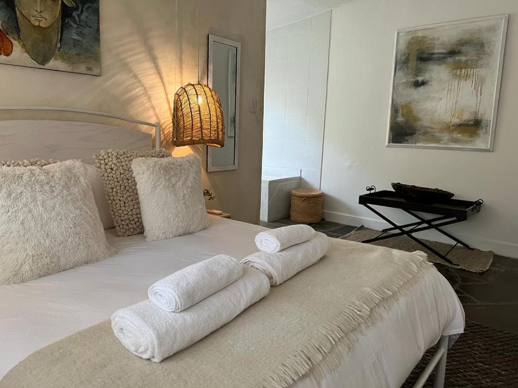 a bedroom with a white bed with towels on it at ENCHANTING SELF-CATERING VILLA with QUEEN BED AT BOKMAKIERIE VILLAS in Windhoek