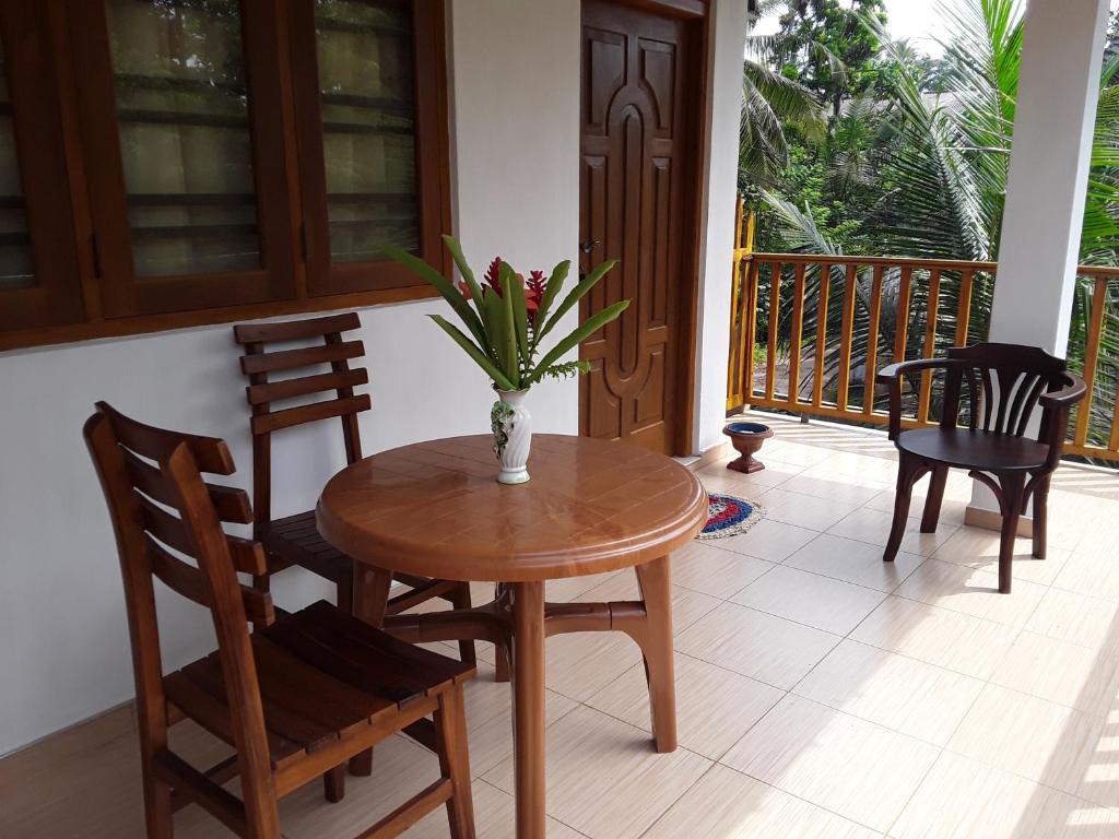 a table with chairs and a vase of flowers on a porch at The Bamboo Leaf Apartment in Hikkaduwa