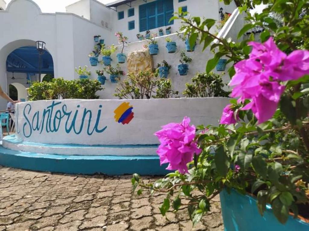 a bench with purple flowers in front of a building at El santorini colombiano en Doradal in Puerto Triunfo