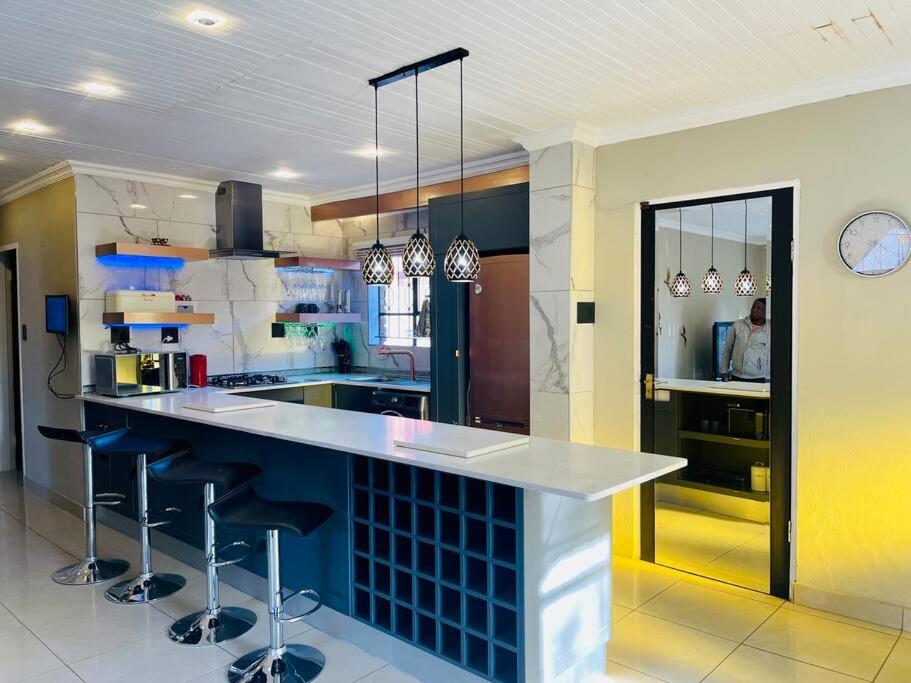 uma cozinha com um balcão com bancos em Mndazi Manor em Pimville