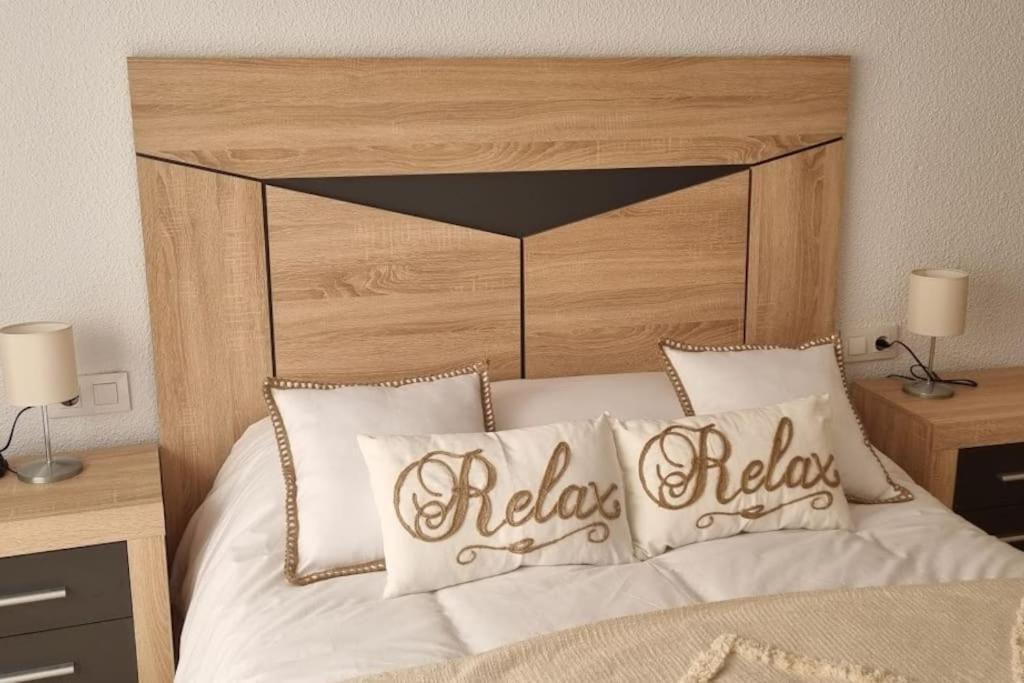 Schlafzimmer mit einem Bett mit einem Kopfteil aus Holz und Kissen in der Unterkunft Piso Puerta del Ángel in Jaén