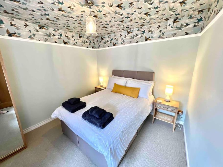 a bedroom with a bed with birds on the ceiling at Penny Black Cottage in Lavenham