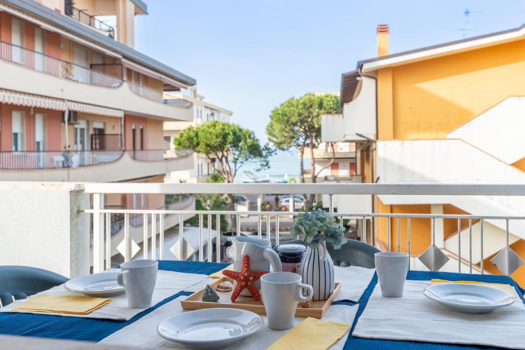 una mesa con platos y tazas en el balcón en Edera 3 Silvi Vacanza, en Silvi Marina